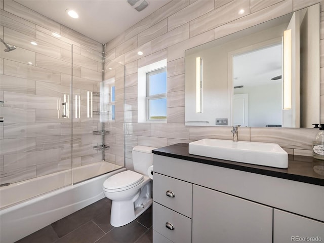 full bathroom with enclosed tub / shower combo, tile walls, toilet, vanity, and tile patterned floors