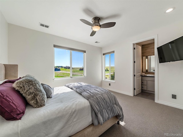 carpeted bedroom with ensuite bath and ceiling fan