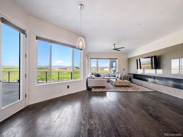 unfurnished living room featuring dark wood-type flooring and ceiling fan