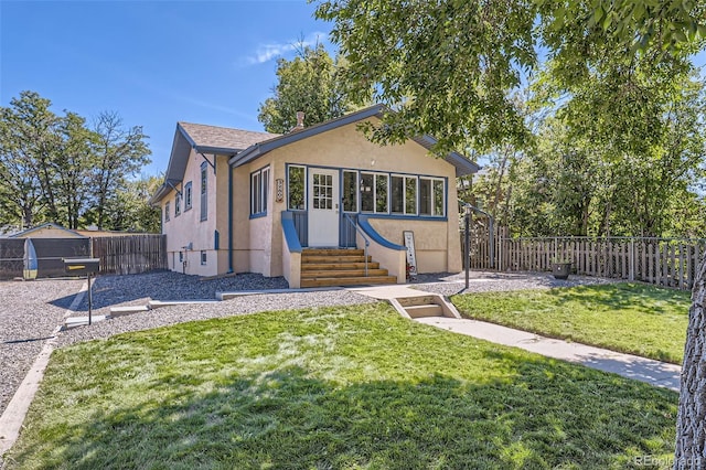 bungalow featuring entry steps, a front yard, a fenced backyard, and stucco siding