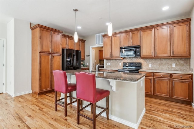 11972 W Long Cir Unit 104, Littleton, CO 80127 - kitchen with black appliances, brown cabinetry, decorative backsplash, light wood-style flooring, and recessed lighting