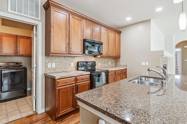 11972 W Long Cir Unit 104, Littleton, CO 80127 - kitchen with washer / dryer, black appliances, arched walkways, tasteful backsplash, and recessed lighting