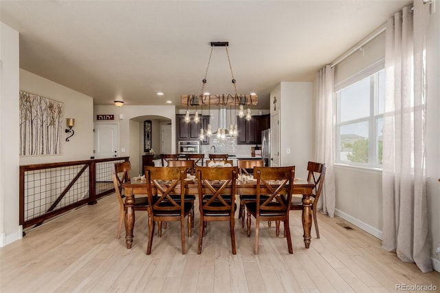 10653 E 163rd Ct, Brighton, CO 80602 - dining area featuring arched walkways, light wood-type flooring, baseboards, and a chandelier