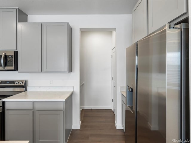 kitchen with appliances with stainless steel finishes, dark hardwood / wood-style floors, and gray cabinetry