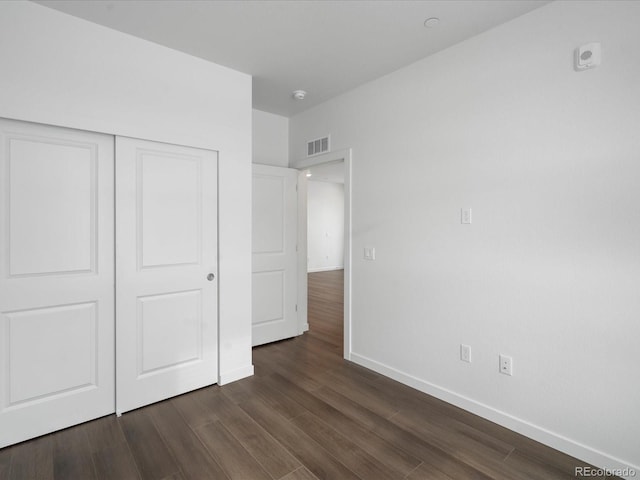 unfurnished bedroom featuring dark hardwood / wood-style floors and a closet