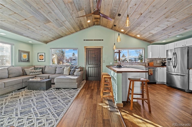 living room featuring a wealth of natural light, dark wood-type flooring, vaulted ceiling, and wooden ceiling
