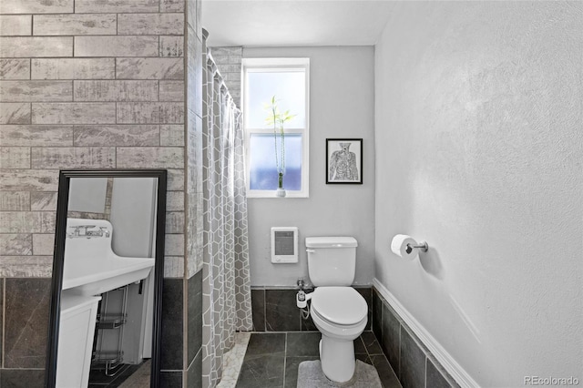 bathroom with heating unit, curtained shower, and toilet