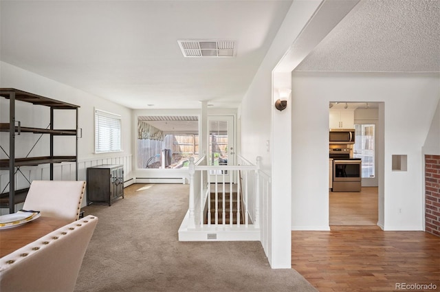 hallway with a baseboard heating unit, wood finished floors, and baseboards