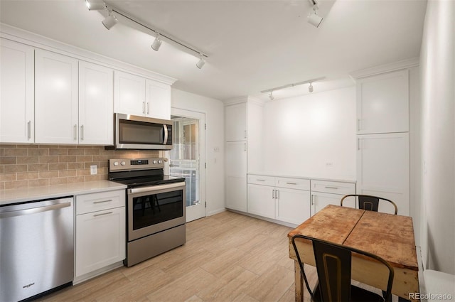 kitchen with stainless steel appliances, track lighting, light countertops, and white cabinetry