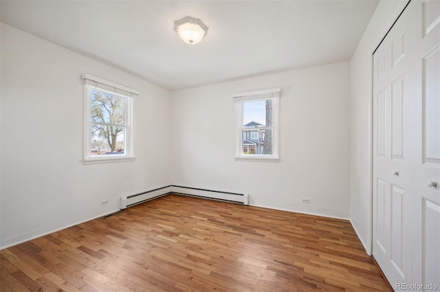 unfurnished bedroom with light wood-style floors, baseboard heating, and a closet