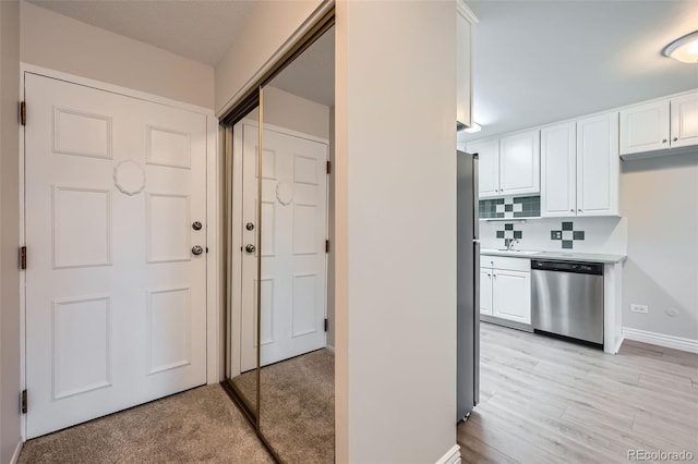 kitchen featuring stainless steel appliances, tasteful backsplash, white cabinets, and light wood-type flooring