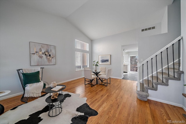 living area with stairway, wood finished floors, visible vents, and baseboards