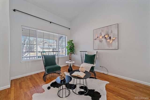 living area featuring lofted ceiling, baseboards, and wood finished floors