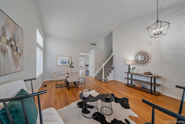 living room featuring high vaulted ceiling, visible vents, stairway, and wood finished floors