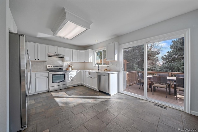 kitchen featuring stainless steel appliances, light countertops, visible vents, backsplash, and white cabinetry