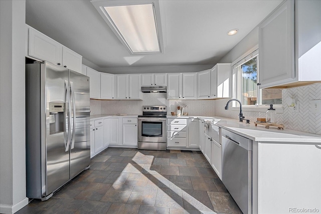 kitchen with a sink, stainless steel appliances, light countertops, under cabinet range hood, and backsplash