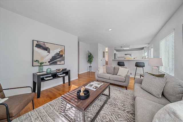 living room with light wood-type flooring, baseboards, and recessed lighting