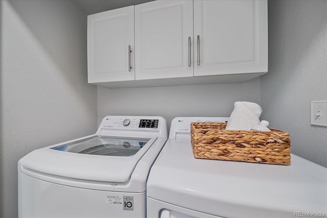 clothes washing area featuring a textured wall, cabinet space, and independent washer and dryer