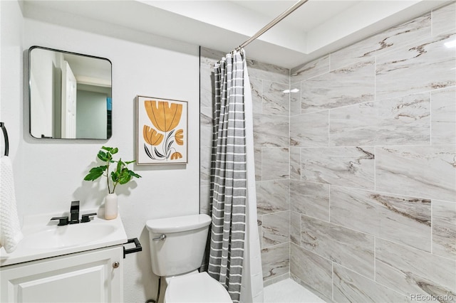 full bathroom featuring tiled shower, vanity, and toilet