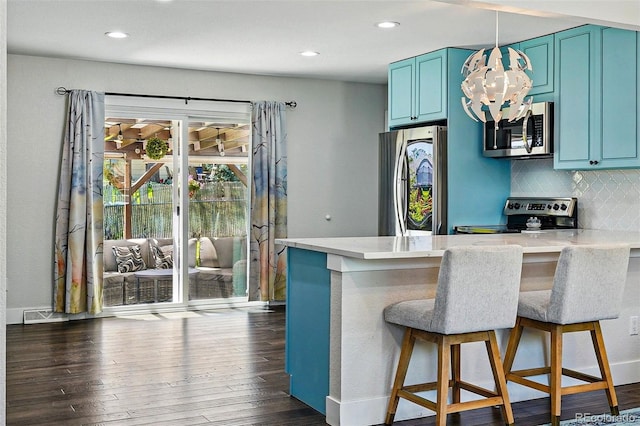 6655 S Elm Cir, Centennial, CO 80121 - kitchen with appliances with stainless steel finishes, blue cabinetry, decorative backsplash, a breakfast bar area, and dark wood-style flooring