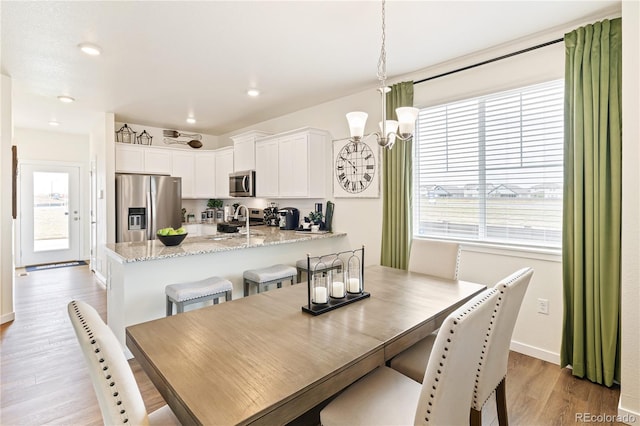 dining space featuring sink, light hardwood / wood-style flooring, and an inviting chandelier