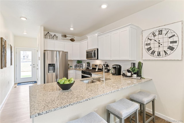 kitchen featuring kitchen peninsula, stainless steel appliances, white cabinets, and sink