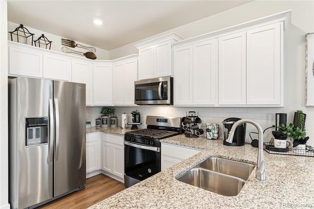 kitchen featuring decorative backsplash, sink, white cabinetry, stainless steel appliances, and light stone counters