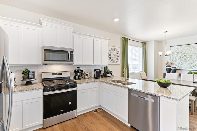 kitchen featuring appliances with stainless steel finishes, a chandelier, white cabinetry, and sink