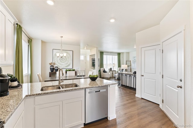 kitchen with white cabinets, hanging light fixtures, stainless steel dishwasher, light stone counters, and sink