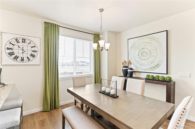 dining area with light wood-type flooring and a chandelier