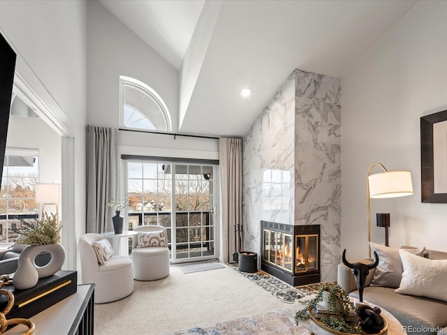 carpeted living room with a high end fireplace and a towering ceiling