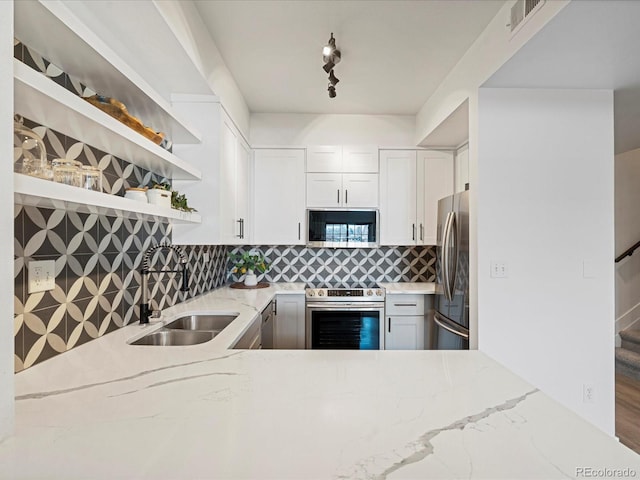 kitchen featuring sink, decorative backsplash, light stone countertops, white cabinetry, and stainless steel appliances