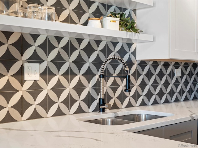 kitchen featuring tasteful backsplash, light stone counters, and sink