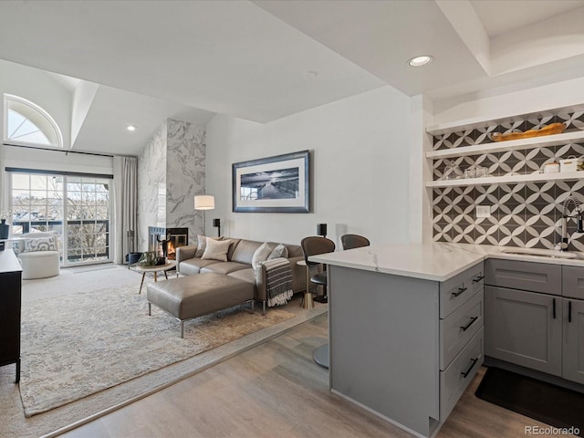 living room featuring a high end fireplace, light hardwood / wood-style floors, and sink