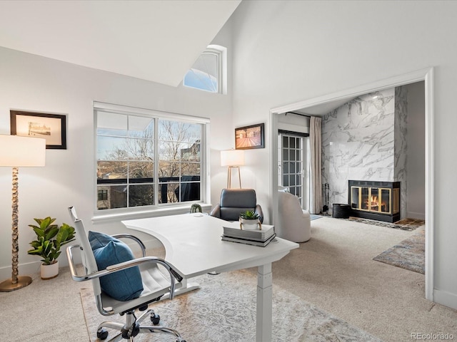 office with a fireplace, high vaulted ceiling, and light colored carpet