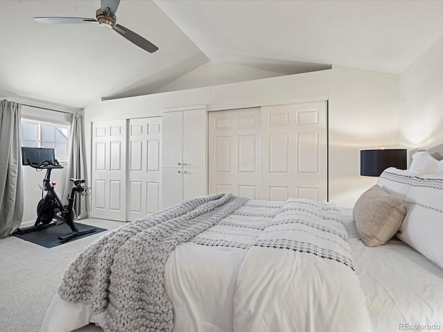 carpeted bedroom with two closets, vaulted ceiling, and ceiling fan