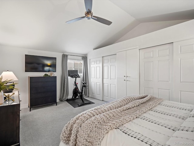 bedroom with lofted ceiling, light carpet, ceiling fan, and two closets