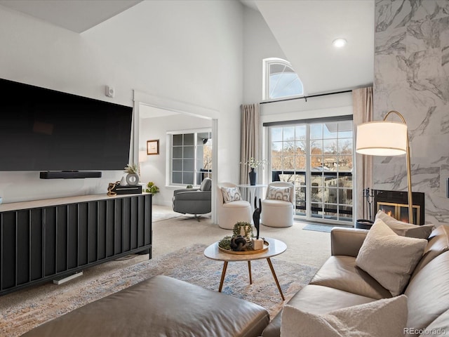 living area with high vaulted ceiling, carpet flooring, and a premium fireplace