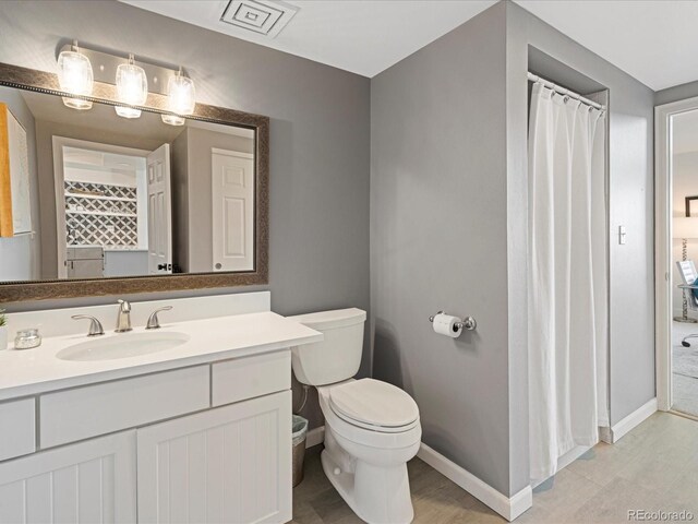 bathroom featuring curtained shower, vanity, toilet, and baseboards
