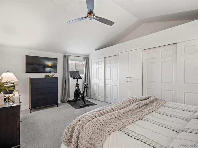 carpeted bedroom with vaulted ceiling, a ceiling fan, and multiple closets