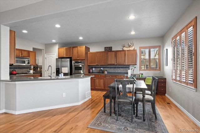 kitchen featuring appliances with stainless steel finishes, light hardwood / wood-style floors, tasteful backsplash, and sink