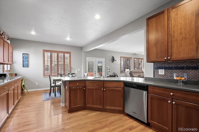 kitchen featuring dishwasher, sink, light wood-type flooring, a textured ceiling, and tasteful backsplash