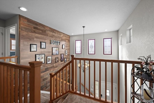 hall featuring a textured ceiling and a notable chandelier