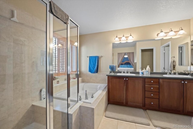 bathroom with tile patterned flooring, shower with separate bathtub, vanity, and a textured ceiling