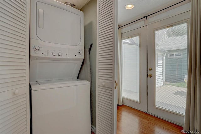 clothes washing area with stacked washer and dryer, light wood-type flooring, and french doors