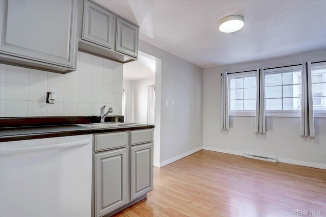 kitchen with dishwasher, tasteful backsplash, light wood-type flooring, gray cabinetry, and sink