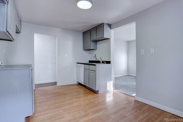 kitchen with sink, dishwasher, light hardwood / wood-style flooring, decorative backsplash, and gray cabinetry