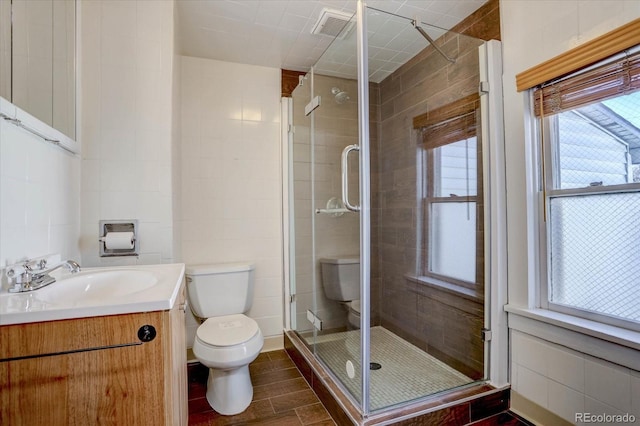 bathroom with toilet, an enclosed shower, vanity, and tile walls