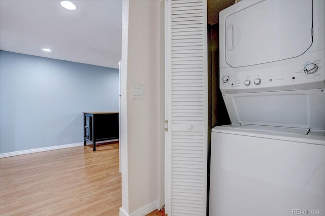 washroom featuring stacked washing maching and dryer and light hardwood / wood-style flooring