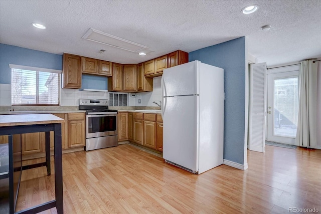 kitchen featuring light hardwood / wood-style floors, white refrigerator, stainless steel electric range oven, a textured ceiling, and sink